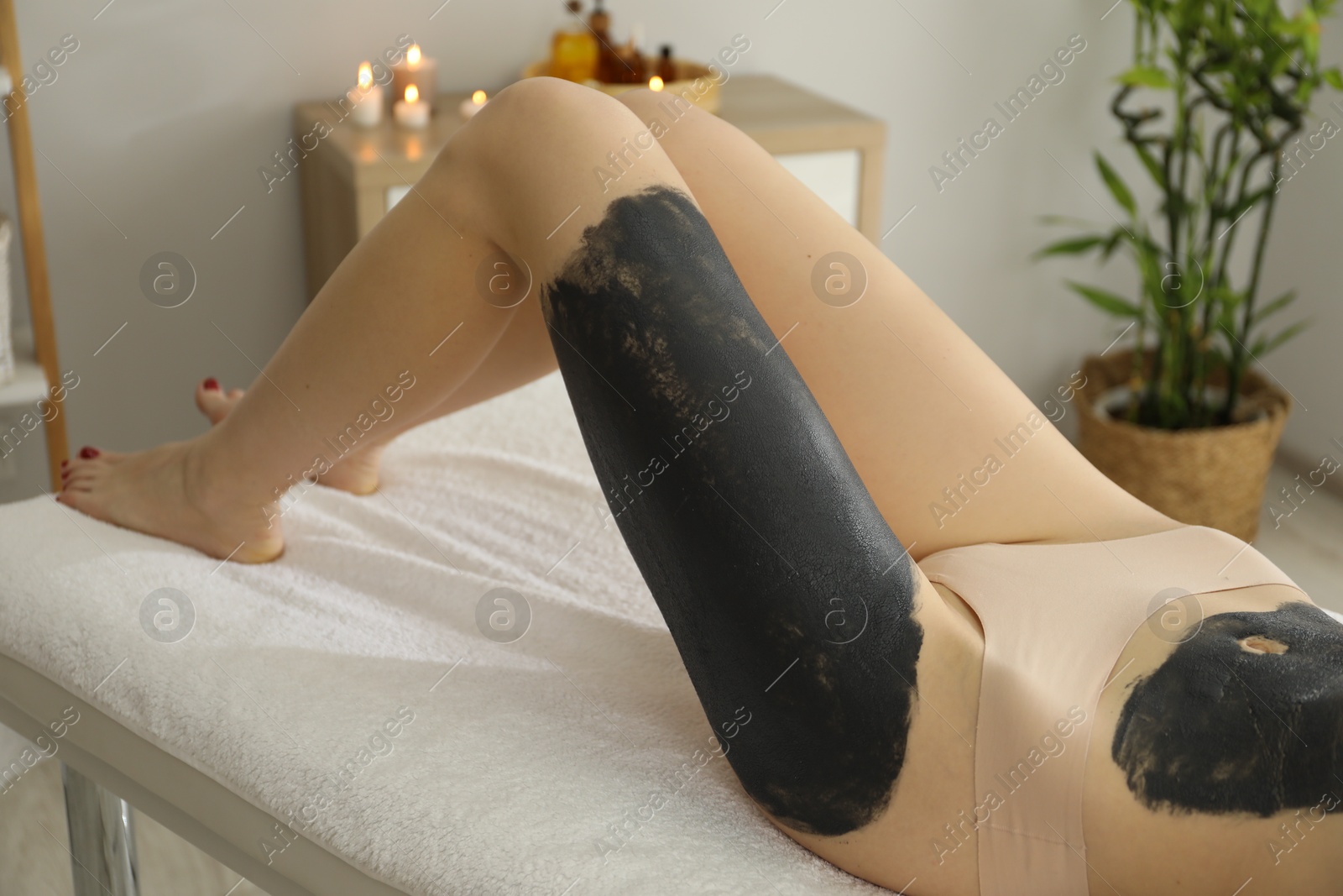 Photo of Woman undergoing body wraps treatment in spa salon, closeup