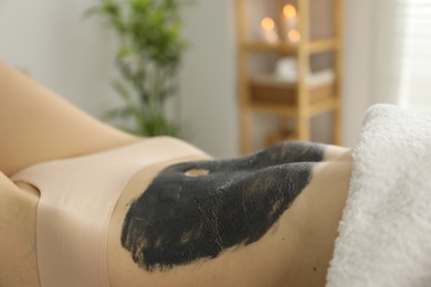 Photo of Woman undergoing body wraps treatment in spa salon, closeup