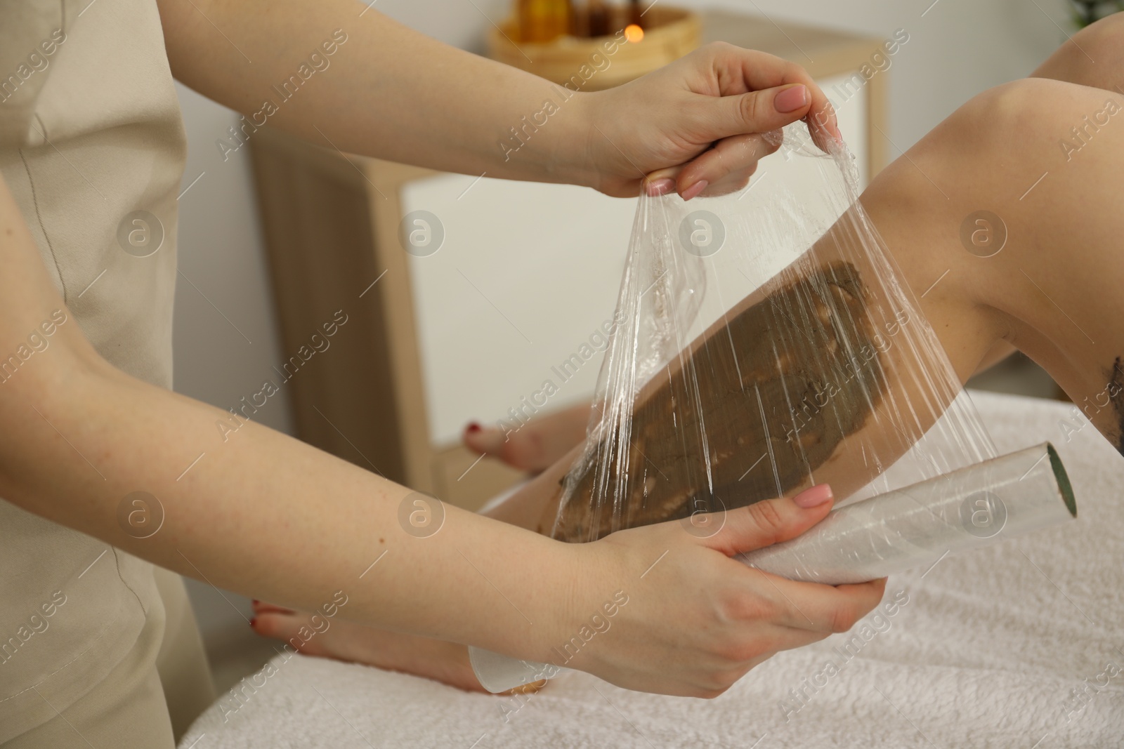 Photo of Woman undergoing body wraps treatment in spa salon, closeup