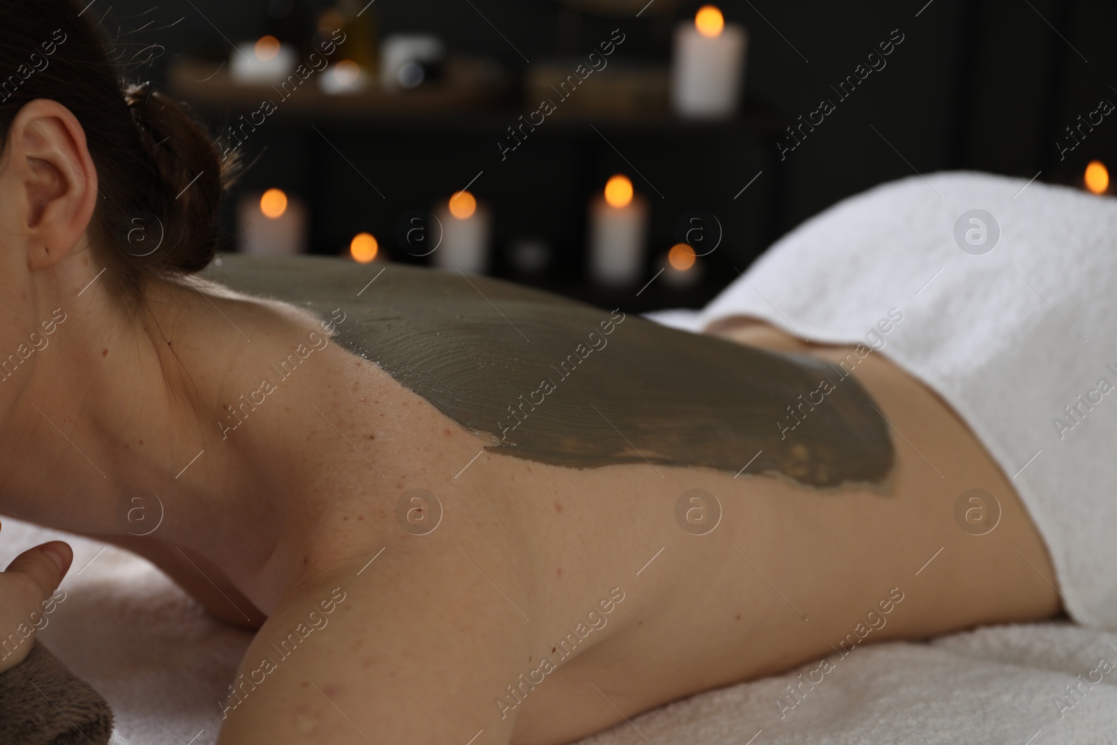 Photo of Woman undergoing body wraps treatment in spa salon, closeup