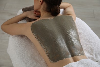 Photo of Woman undergoing body wraps treatment in spa salon, closeup