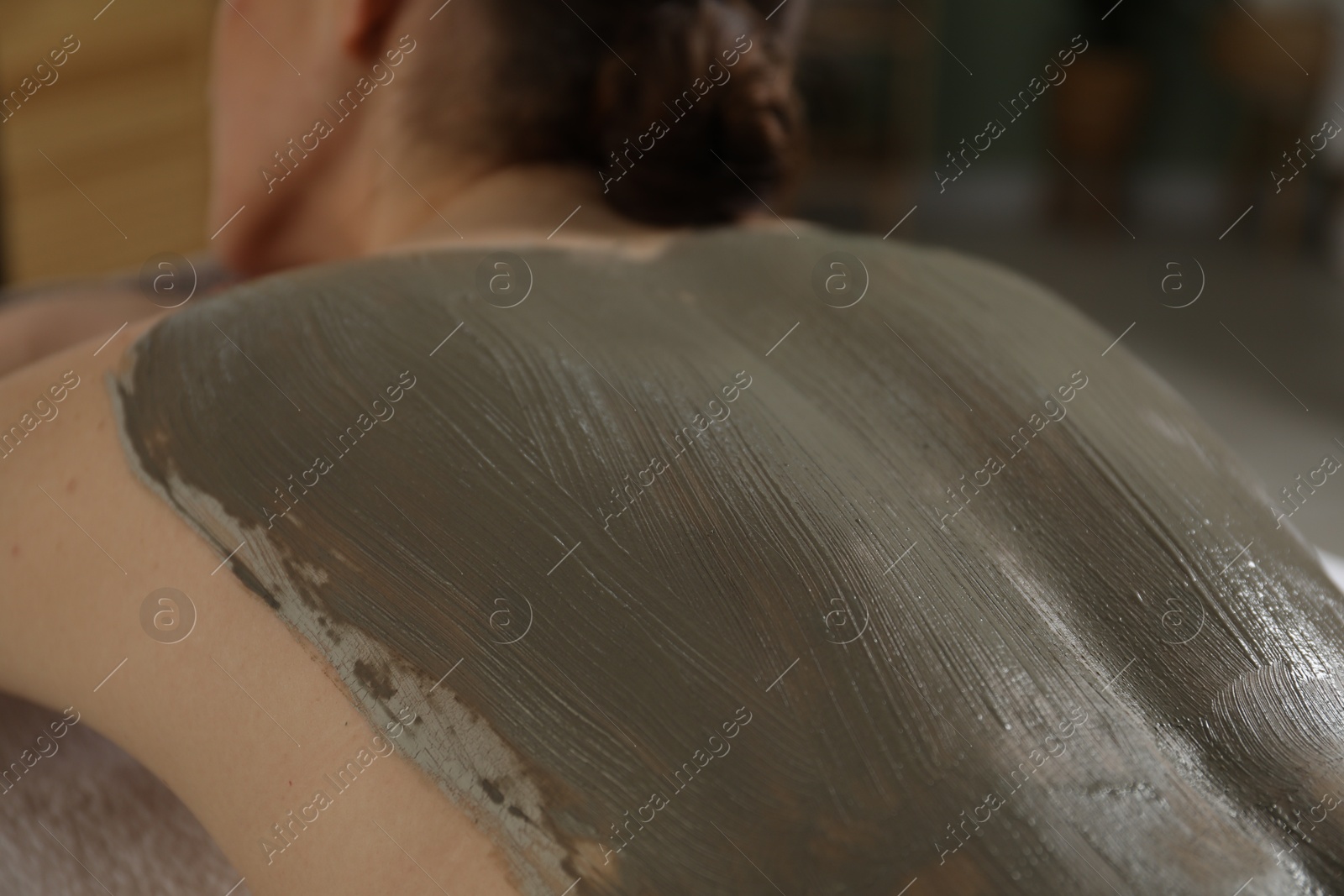 Photo of Woman undergoing body wraps treatment in spa salon, closeup