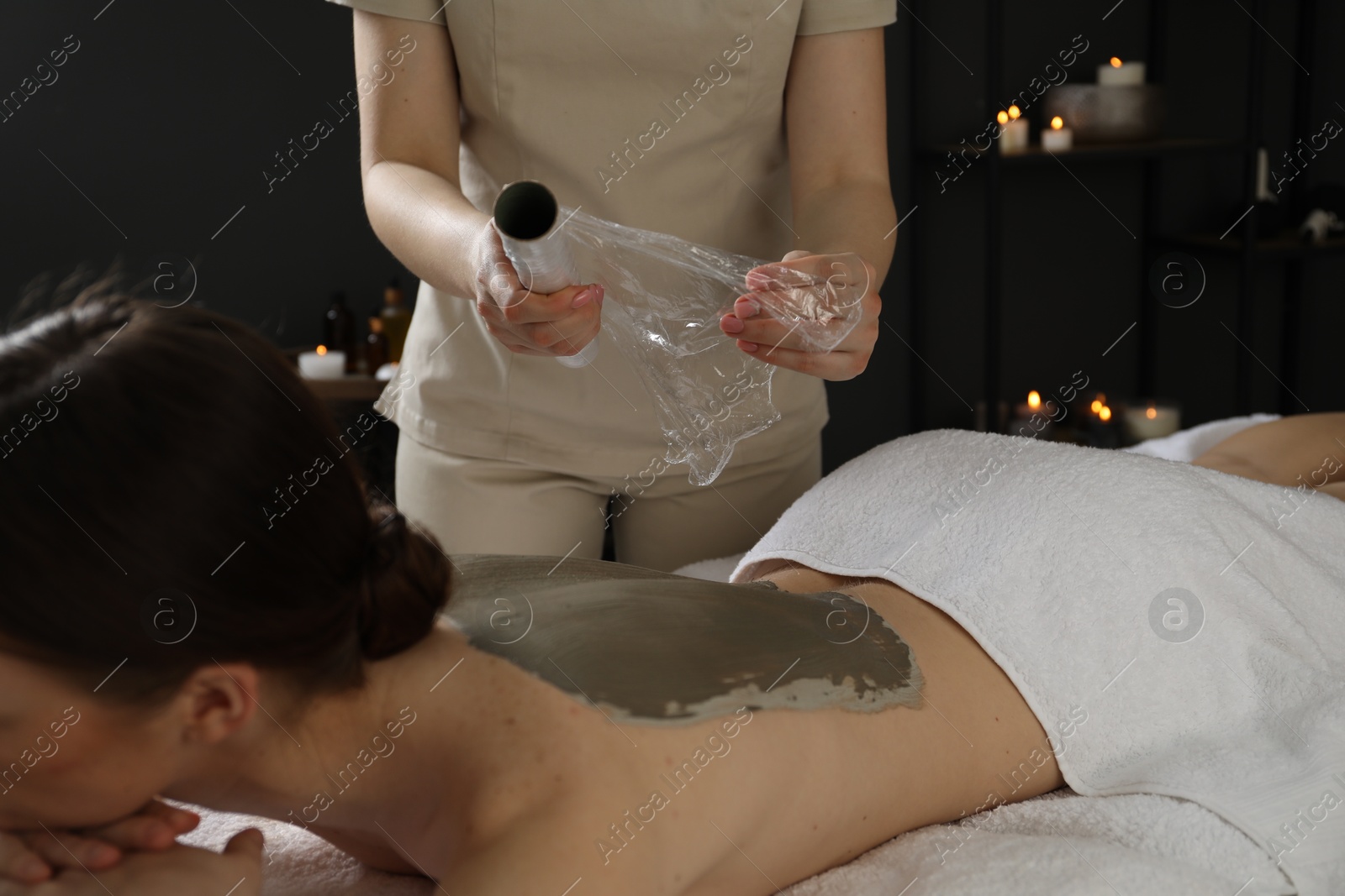 Photo of Woman undergoing body wraps treatment in spa salon, closeup