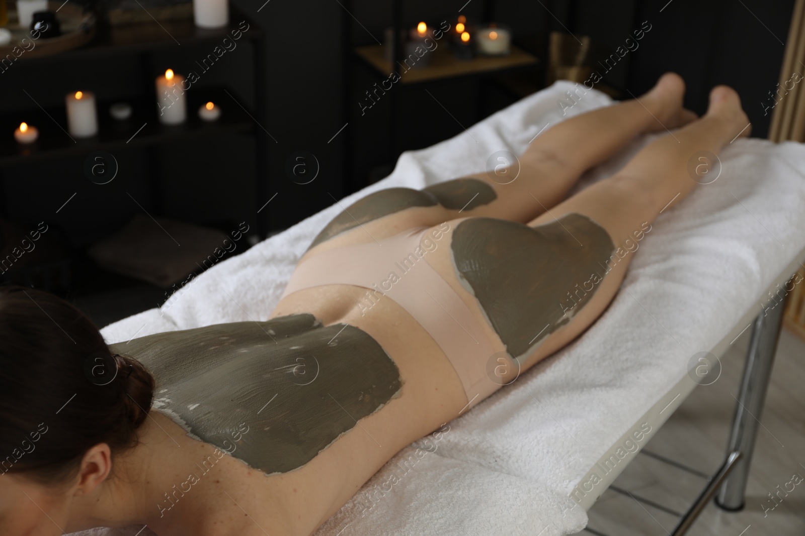 Photo of Woman undergoing body wraps treatment in spa salon, closeup