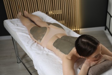 Woman undergoing body wraps treatment in spa salon