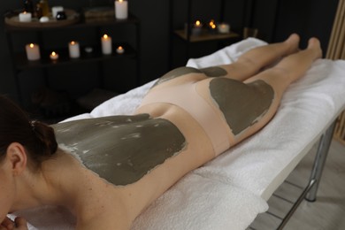 Photo of Woman undergoing body wraps treatment in spa salon, closeup