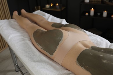 Photo of Woman undergoing body wraps treatment in spa salon, closeup