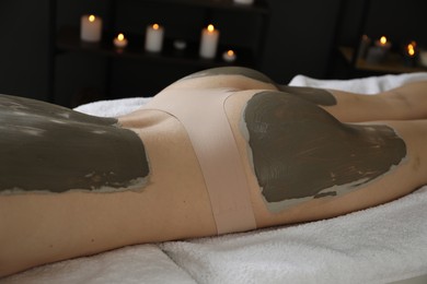 Woman undergoing body wraps treatment in spa salon, closeup