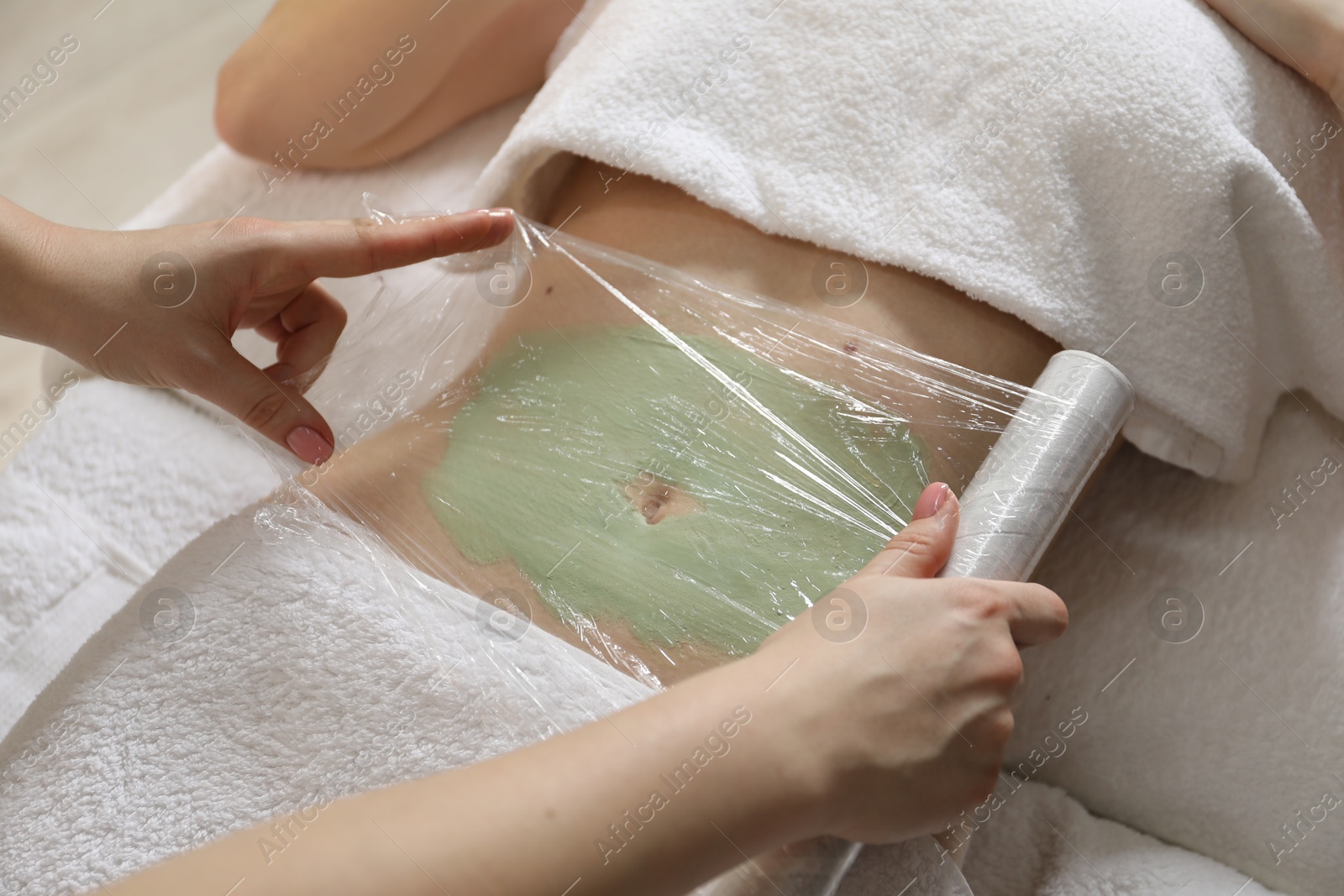 Photo of Woman undergoing body wraps treatment in spa salon, closeup