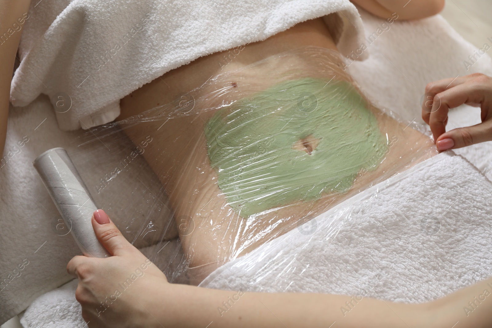 Photo of Woman undergoing body wraps treatment in spa salon, closeup