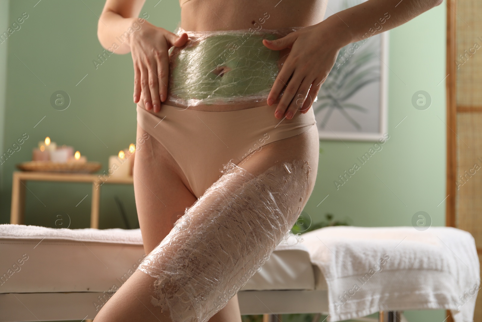 Photo of Woman doing spa body wraps on in salon, closeup