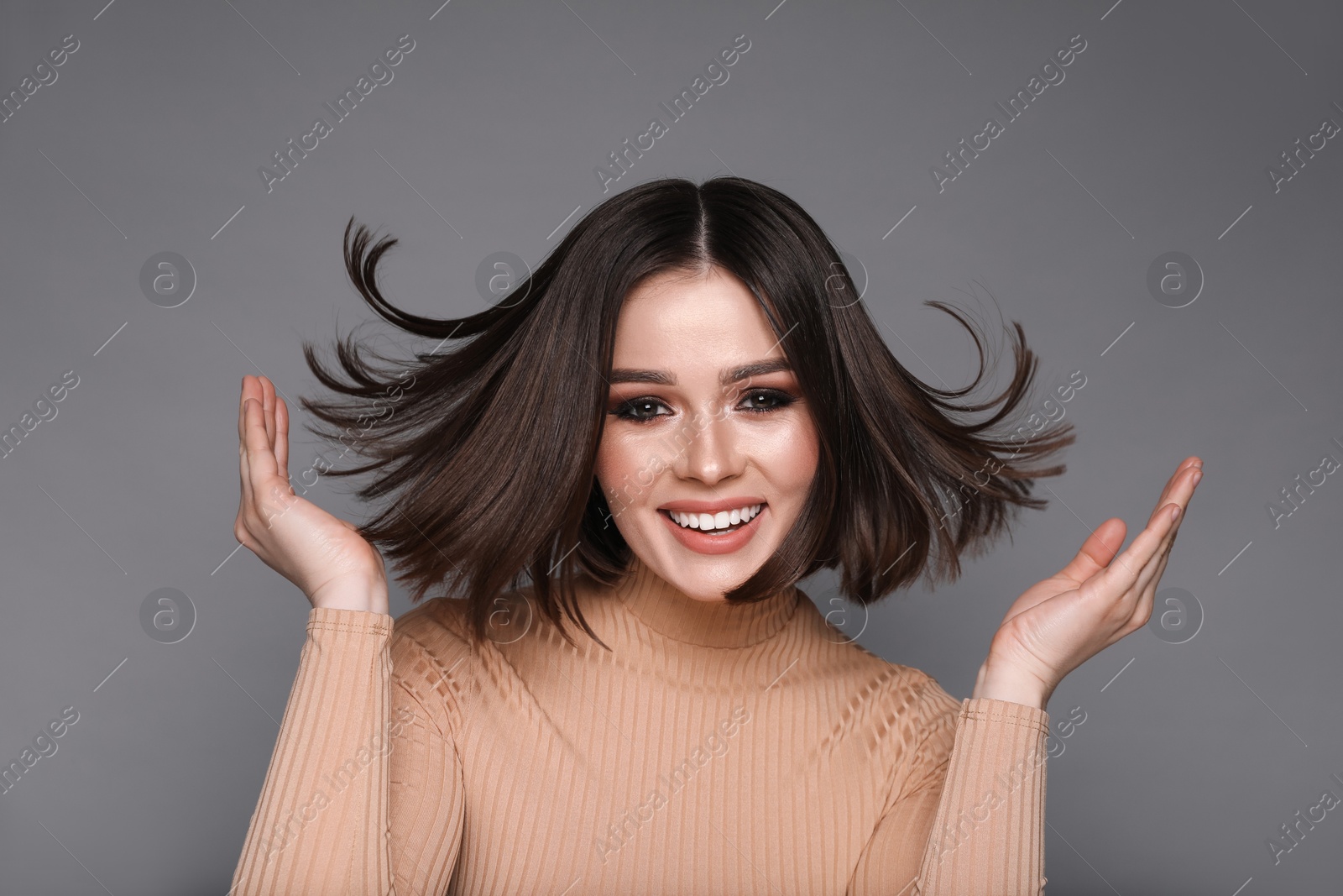 Photo of Portrait of beautiful young happy woman with gorgeous straight hair on grey background