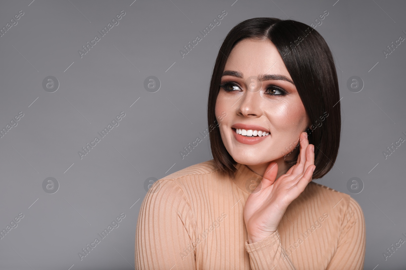 Photo of Portrait of beautiful young happy woman with gorgeous straight hair on grey background, space for text