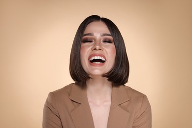 Portrait of beautiful young happy woman with gorgeous straight hair on beige background