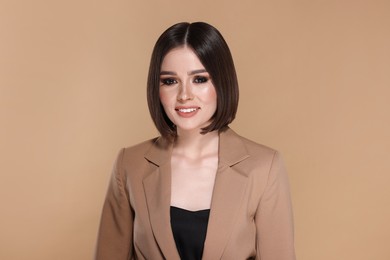 Portrait of beautiful young happy woman with gorgeous straight hair on beige background