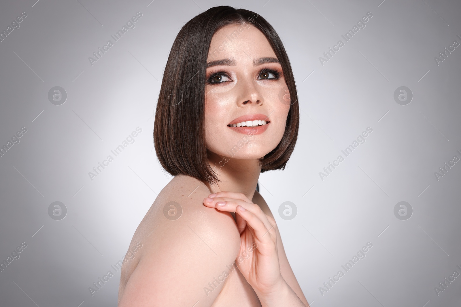 Photo of Portrait of beautiful young happy woman with gorgeous straight hair on light grey background