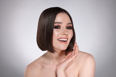 Photo of Portrait of beautiful young happy woman with gorgeous straight hair on light grey background