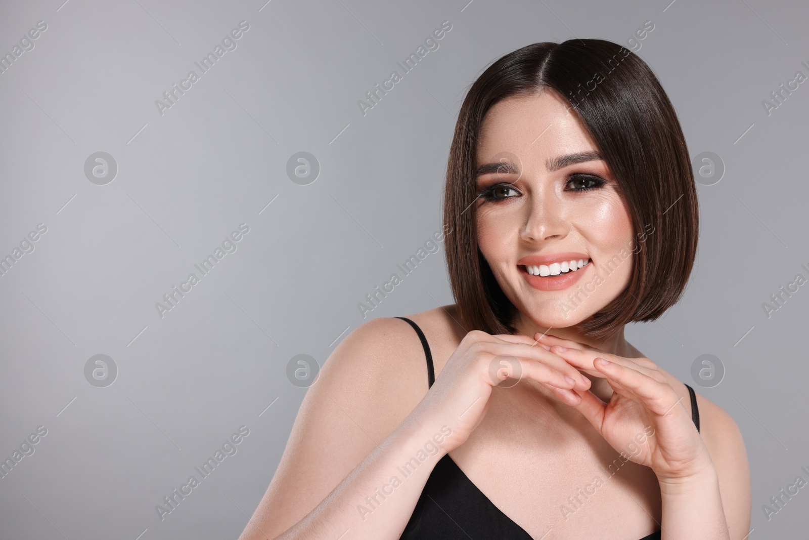 Photo of Portrait of beautiful young happy woman with gorgeous straight hair on light grey background, space for text