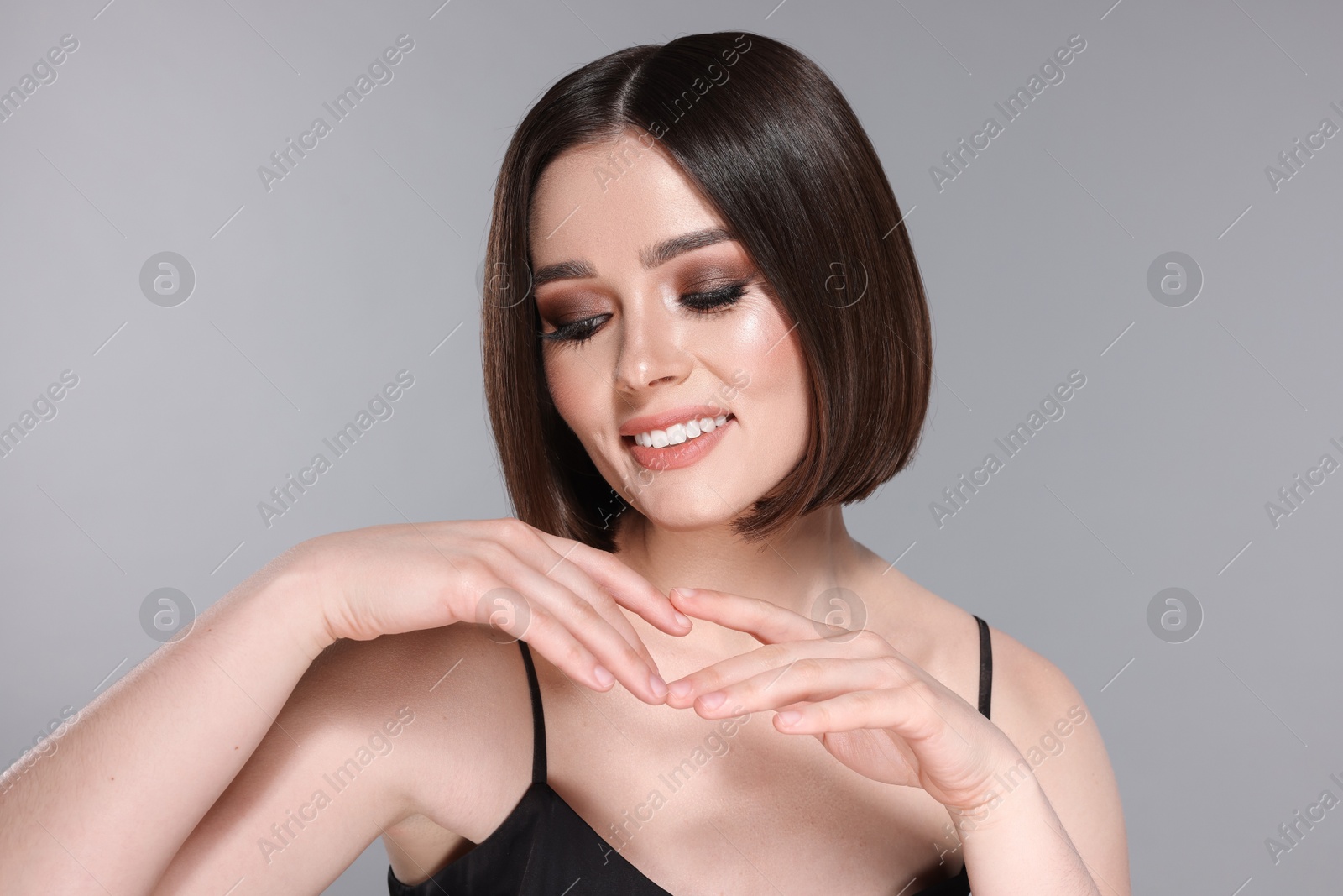 Photo of Portrait of beautiful young happy woman with gorgeous straight hair on light grey background