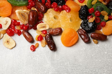 Photo of Mix of different dried fruits on gray textured table, top view. Space for text