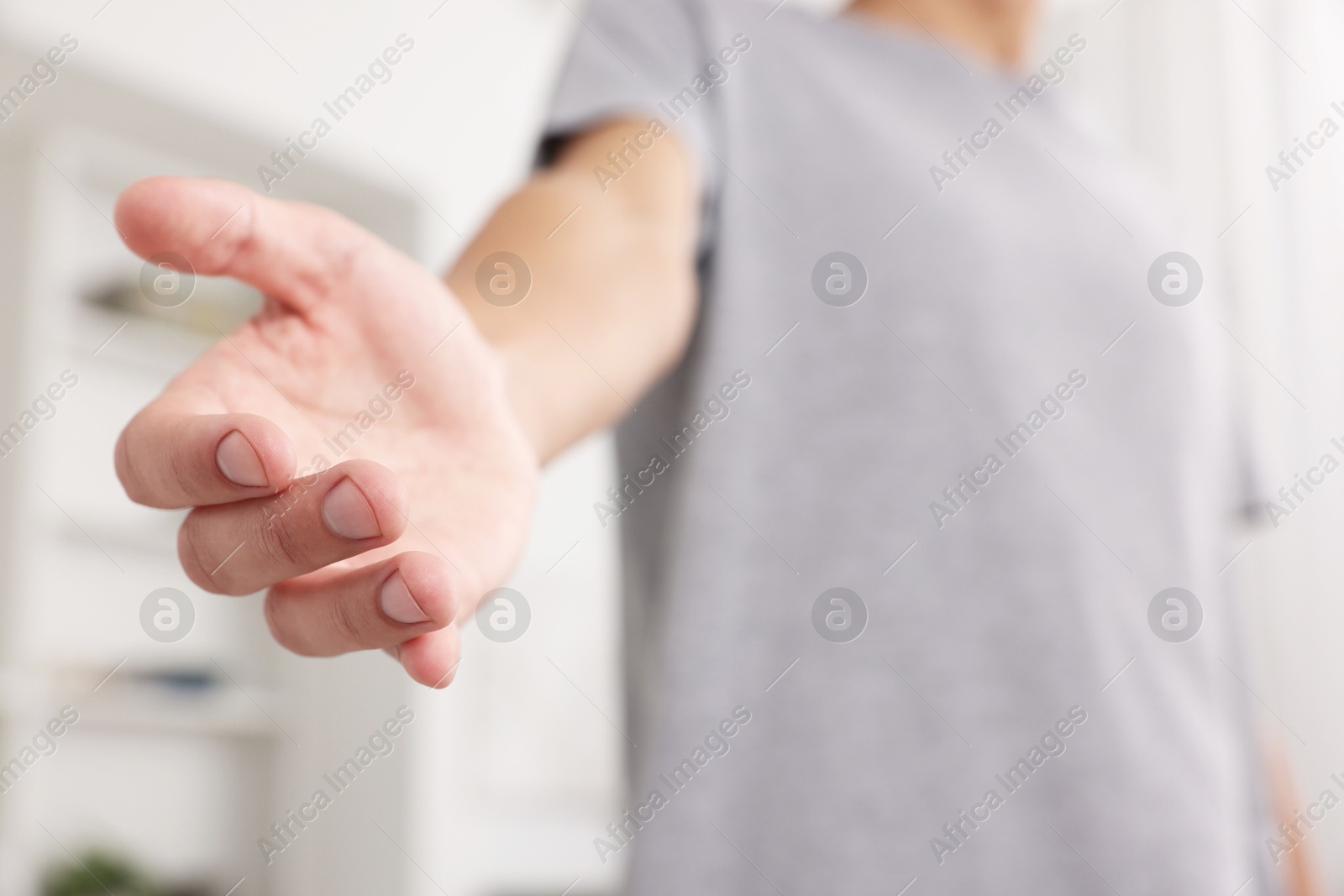 Photo of Offering help. Man reaching his hand indoors, closeup