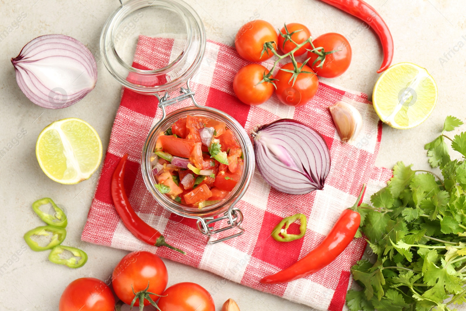 Photo of Delicious salsa (Pico de gallo) in jar and ingredients on light textured table, flat lay