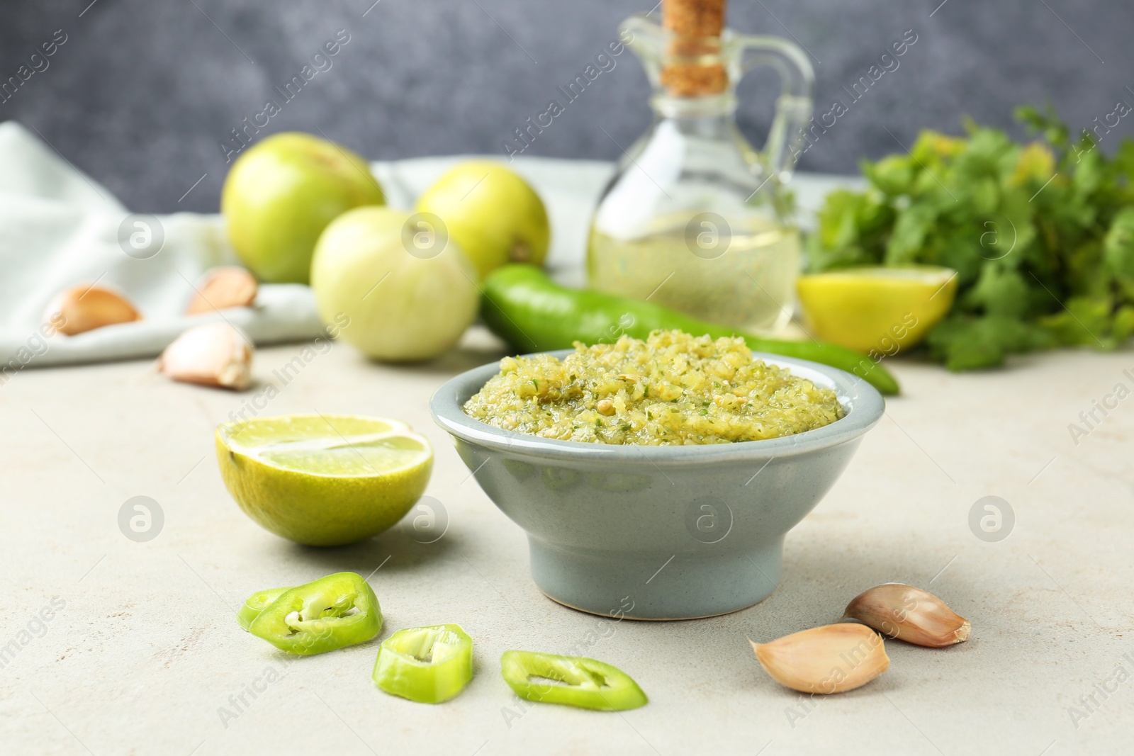 Photo of Delicious salsa sauce in bowl and products on light textured table, closeup