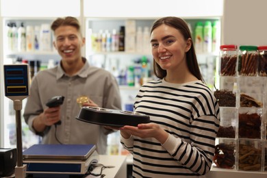 Photo of Woman buying food and bowls in pet shop, selective focus