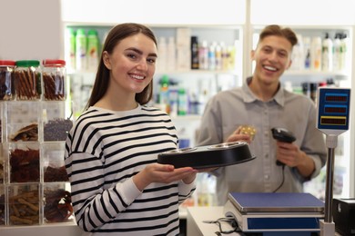 Photo of Woman buying food and bowls in pet shop, selective focus