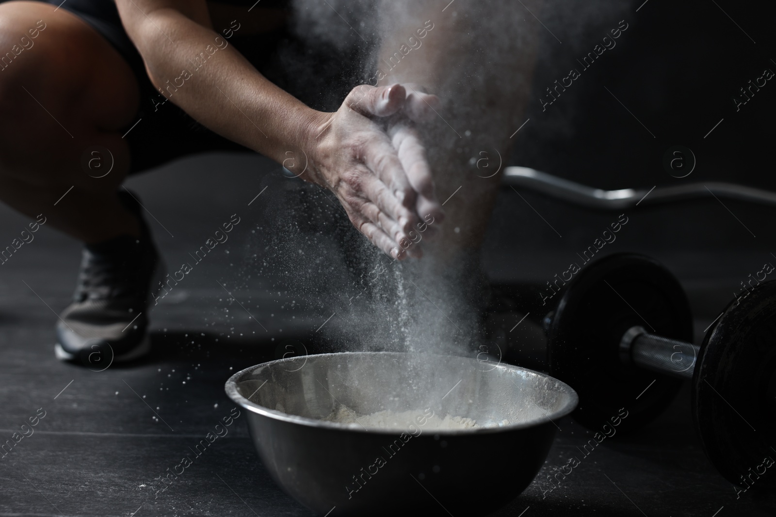 Photo of Woman clapping hands with talcum powder above bowl before training in gym, closeup