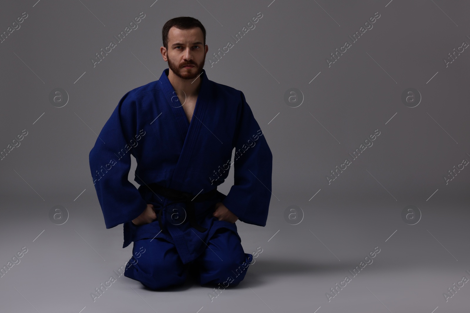 Photo of Karate fighter in uniform on grey background