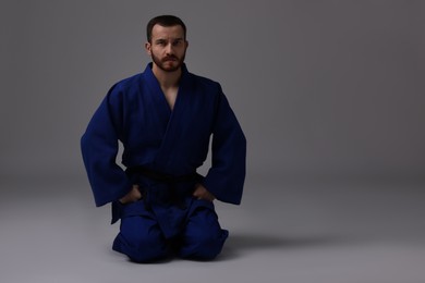 Photo of Karate fighter in uniform on grey background