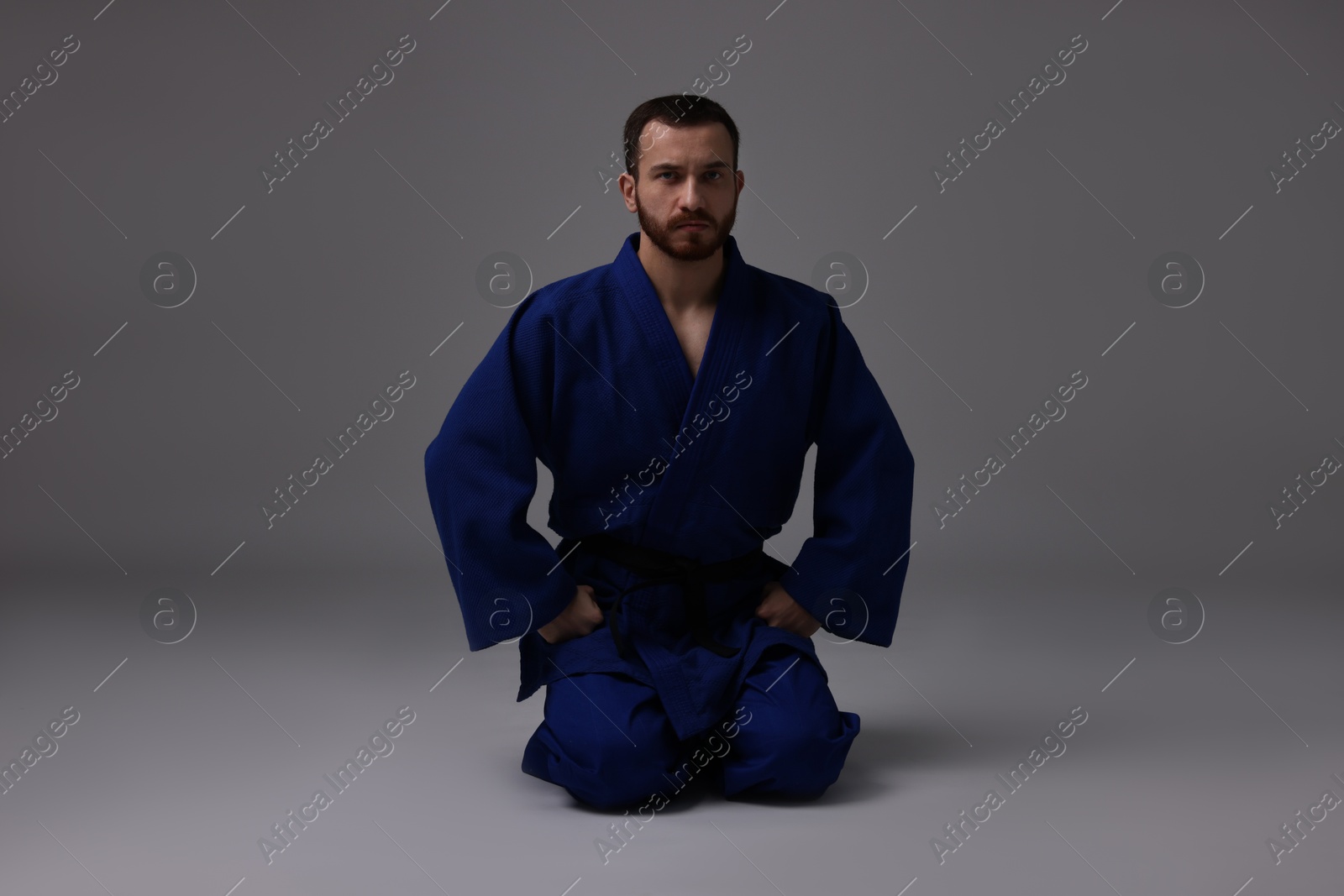 Photo of Karate fighter in uniform on grey background