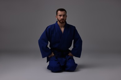 Photo of Karate fighter in uniform on grey background