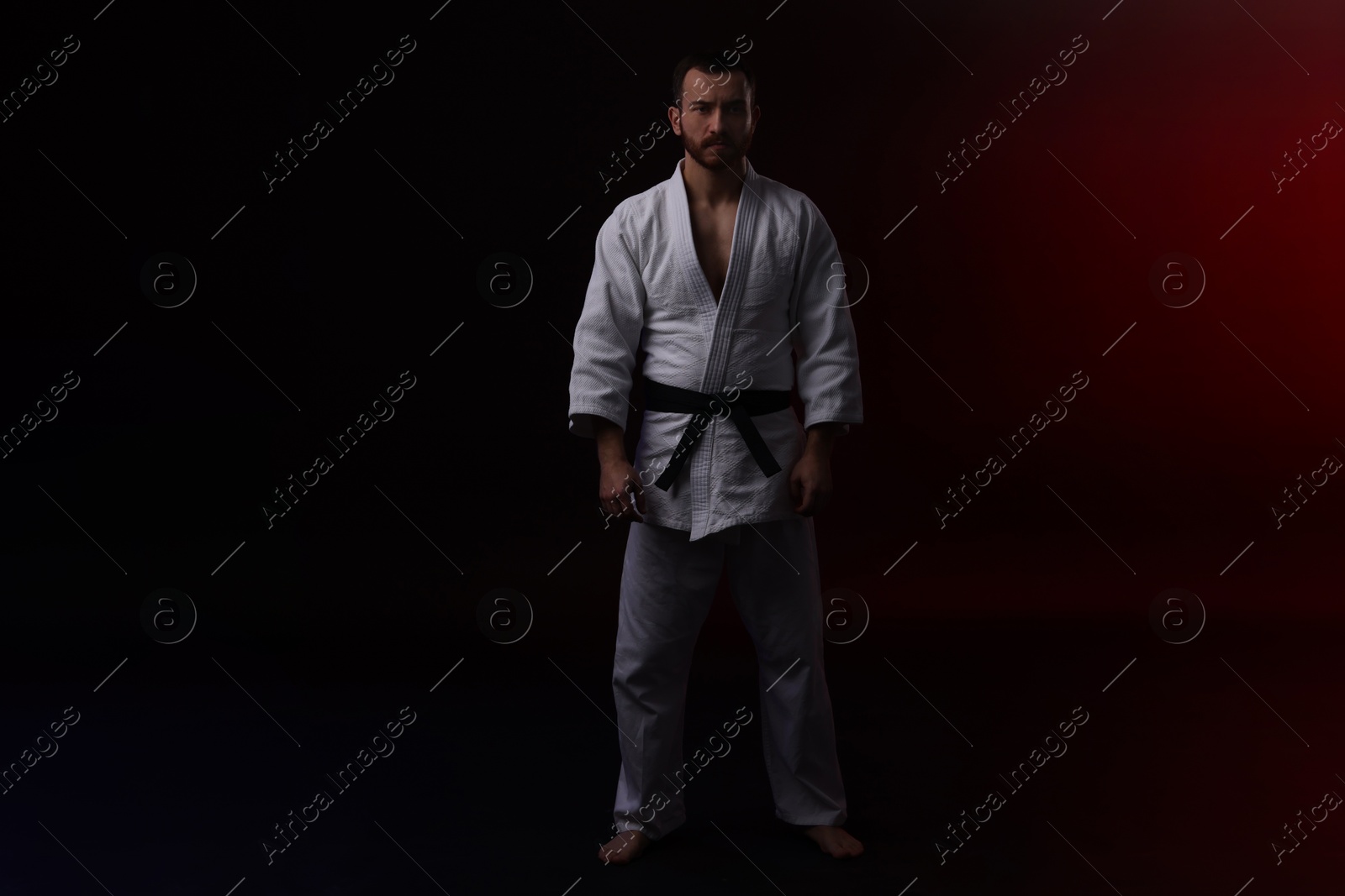 Photo of Karate fighter in uniform on black background