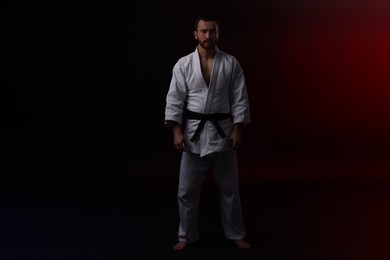 Photo of Karate fighter in uniform on black background