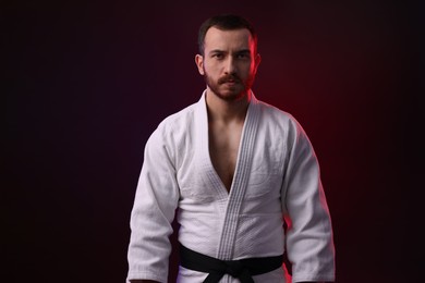 Photo of Karate fighter wearing uniform in color light against black background