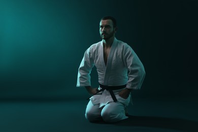 Photo of Karate fighter wearing uniform in color lights. Space for text