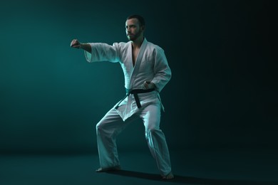 Photo of Man wearing uniform practicing karate in color lights