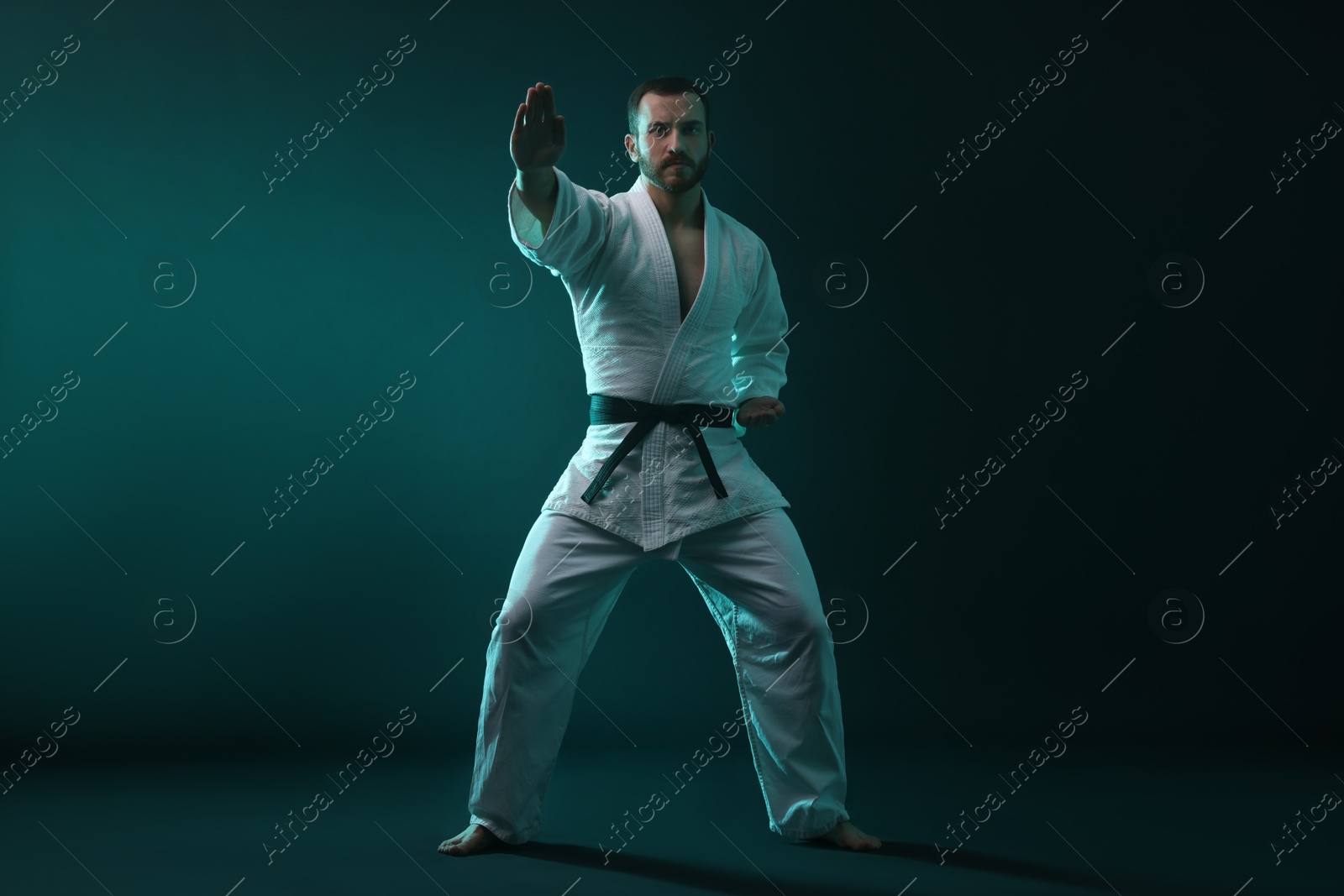 Photo of Man wearing uniform practicing karate in color lights