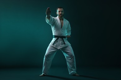 Photo of Man wearing uniform practicing karate in color lights