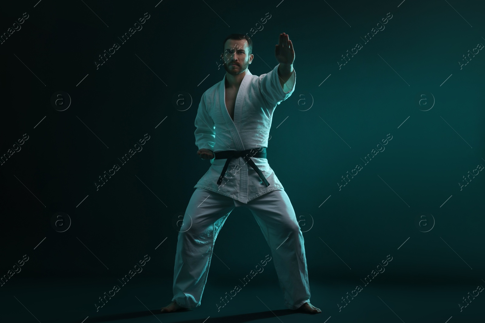 Photo of Man wearing uniform practicing karate in color lights