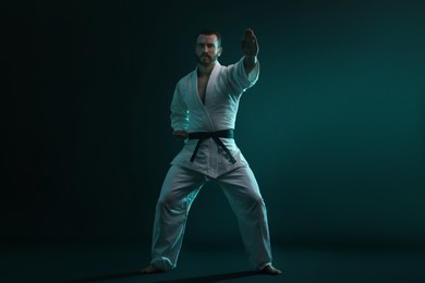 Photo of Man wearing uniform practicing karate in color lights