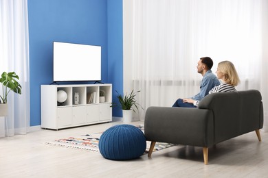 Lovely couple watching tv on couch at home