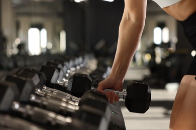 Sportswoman with dumbbells during crossfit workout in gym, closeup. Space for text