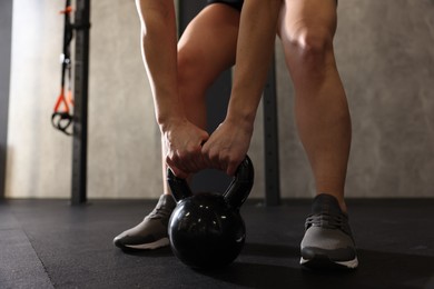 Sportswoman doing kettlebell swing during crossfit workout in gym, closeup