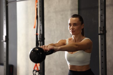 Sportswoman doing kettlebell swing during crossfit workout in gym. Space for text