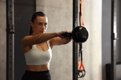 Photo of Sportswoman doing kettlebell swing during crossfit workout in gym