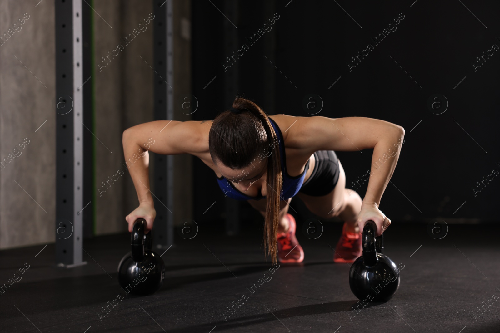 Photo of Sportswoman doing kettlebell push up during crossfit workout in gym