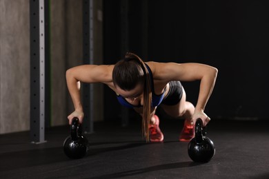 Photo of Sportswoman doing kettlebell push up during crossfit workout in gym